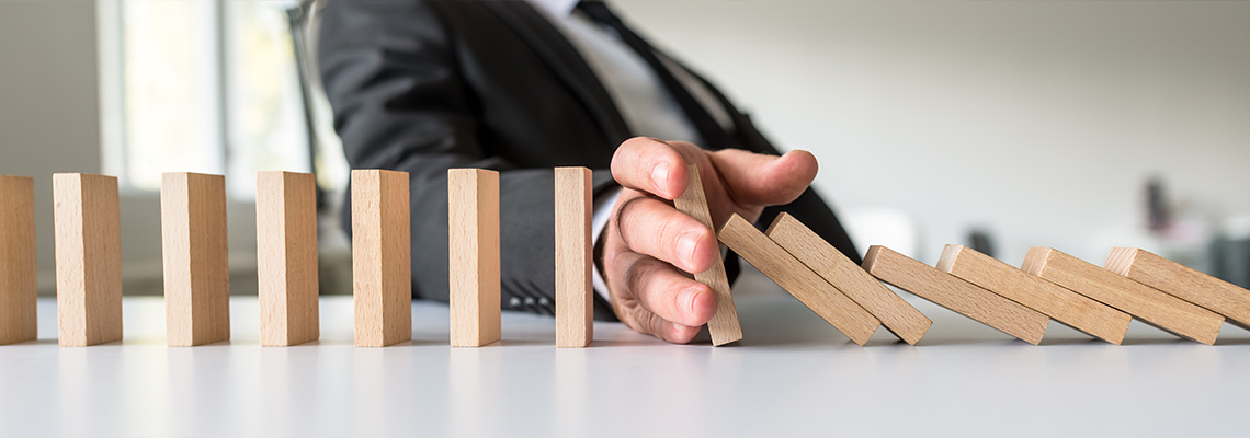 Man in suit stopping line of blocks from falling with his hand