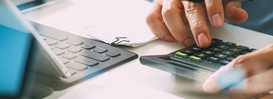 Person at a desk with a laptop and calculator