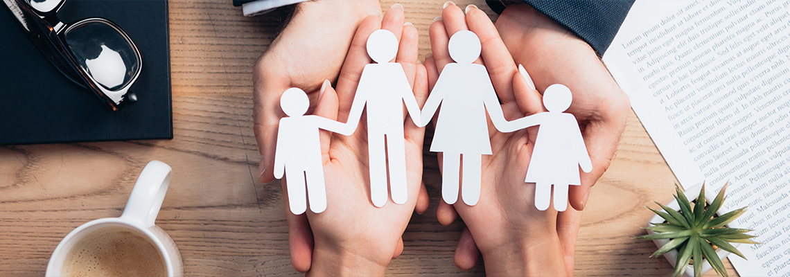 Two people holding paper cutouts of a family in their hands