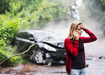 young woman by the damaged car after accident