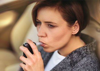 Young millennial woman using breath alcohol analyzer