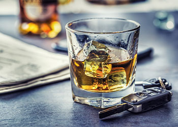 Car keys and glass of alcohol on table in pub