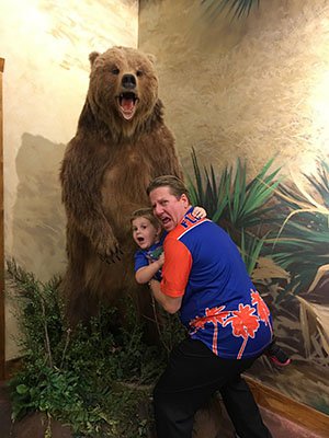 Attorney J. Jason Bangos Holding his Son and Standing by a Bear Sculpture