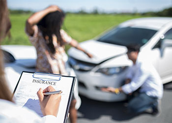 Insurance agent examining car after accident