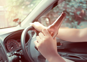 Man drink beer while driving car.