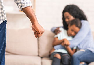 Woman and young girl cowering as a man stands with a clenched fist