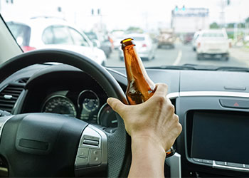 A driver holding alcoholic bottle while driving