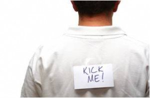 Man facing away with "kick me!" sign on back