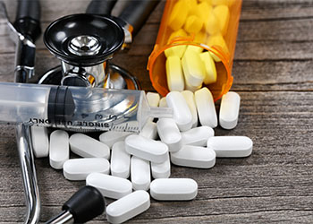 Pills, a syringe, and a stethoscope on a table