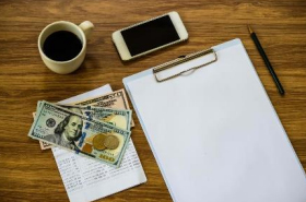 Clipboard, cash, coffee, and cell phone on desk