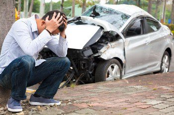 Man crouched near a wrecked car in need of a vehicular manslaughter lawyer in Orange County, CA