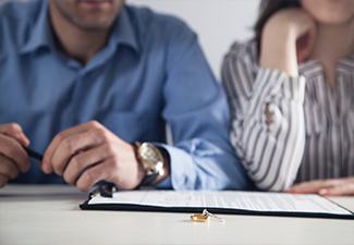 Couple with divorce contract and ring on desk.