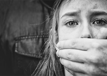 Man's hand covering mouth of scared young girl