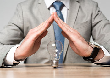 Man showing protection gesture above light bulb