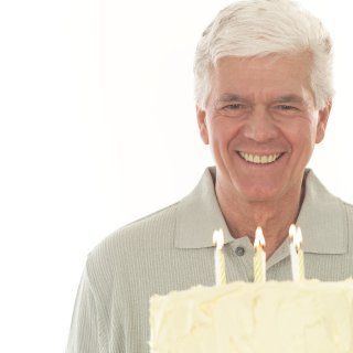 older man looking at cake with candles on it