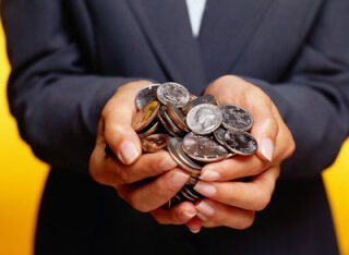 person in suit with hands full of coins