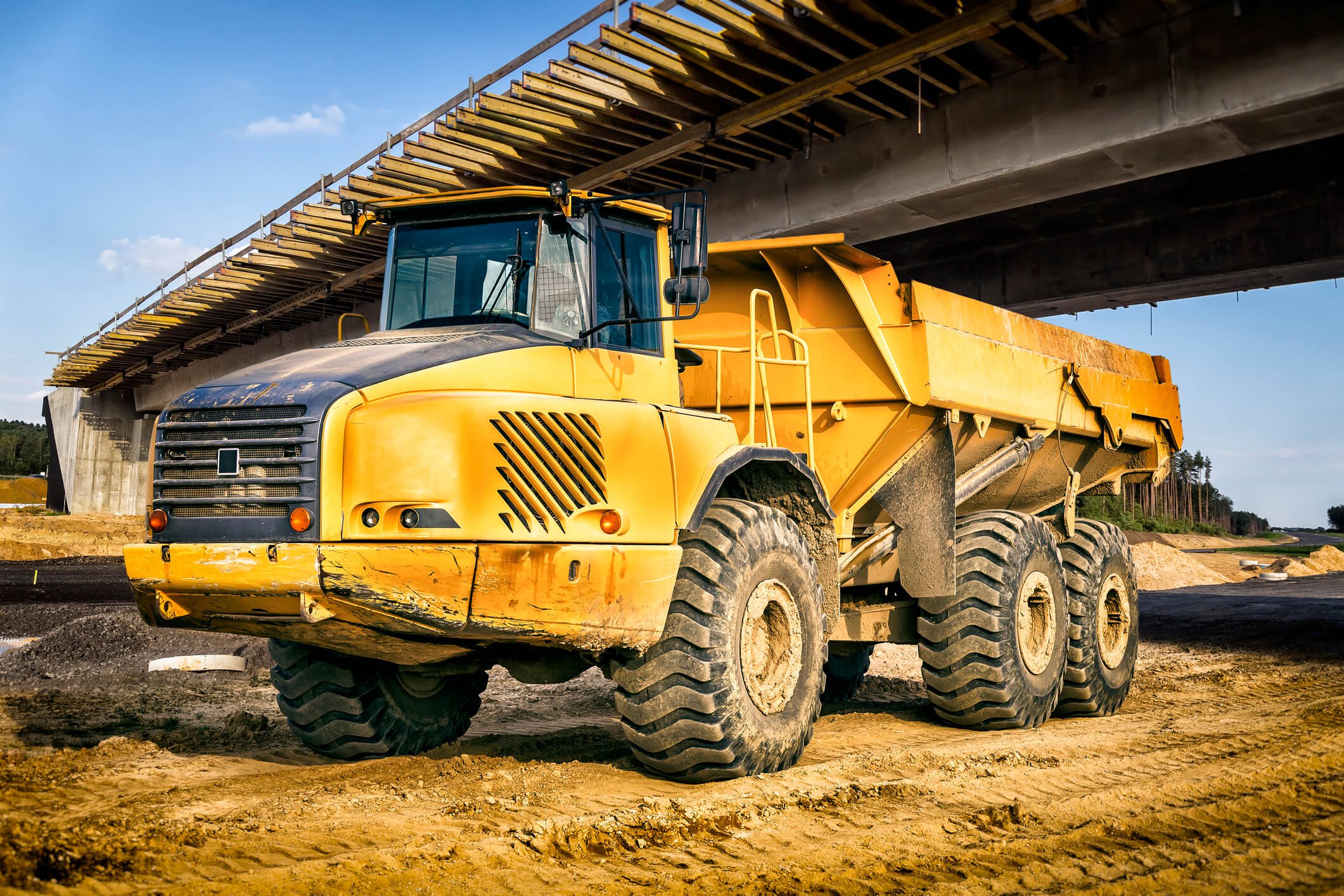 Yellow construction truck under highway