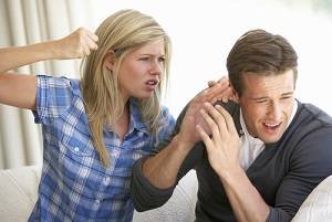 Woman holding up fist to man on couch