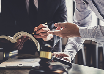 Two people in suits at desk with paperwork and gavel