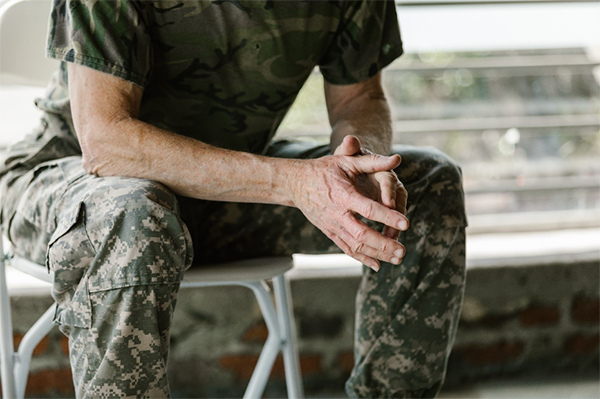 Person in army camo outfit sitting on bench