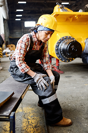 Injured worker with hard hat holding her knee