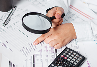 Businessman Using Magnifying to Review Balance Sheet Annual