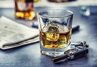 Car keys and glass of alcohol on table in pub or restaurant.