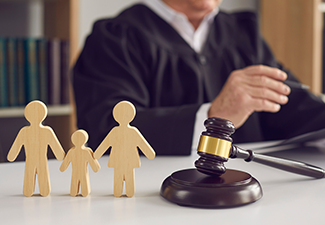 Gavel,  small wooden figurines of husband, wife and kid on judge's table.