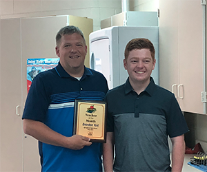 Brandon Yost posing with student and plaque 