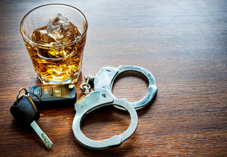 A Glass of Alcohol, Car Key and Handcuff on A Wooden Table