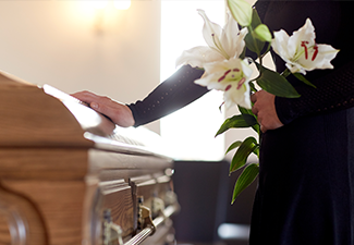 Woman with lily flowers and coffin at funeral.