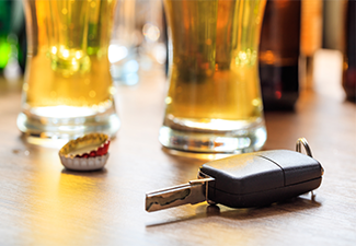 Drinking and driving. Car key on a wooden bar counter.