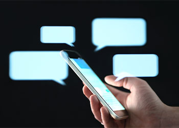 Text messages in cellphone with abstract hologram speech bubbles