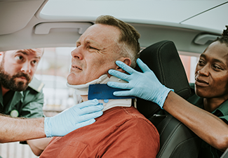 Paramedic placing a cervical collar to an injured man from car accident.