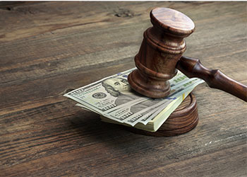 Wooden gavel sitting on top of pile of money