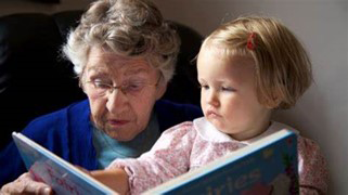 Older person sitting with young child looking at picture book