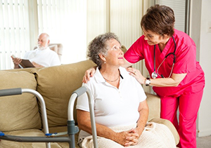 Older person sitting and smiling up at younger person in scrubs