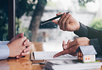 Real estate agent holding house key to his client after signing.