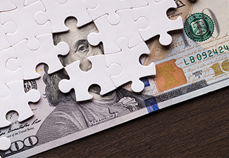 American dollar hidden under puzzle pieces.