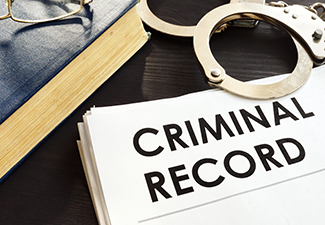 Criminal record and handcuffs on a desk.