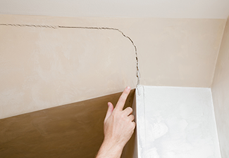 Man's Hand Finger Pointing to The Cracked Wall in House