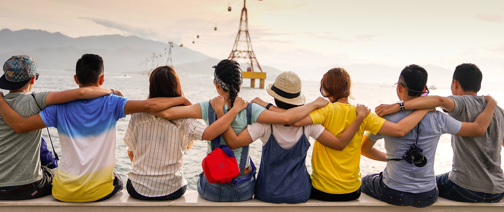 Travelers linking arms together by the water