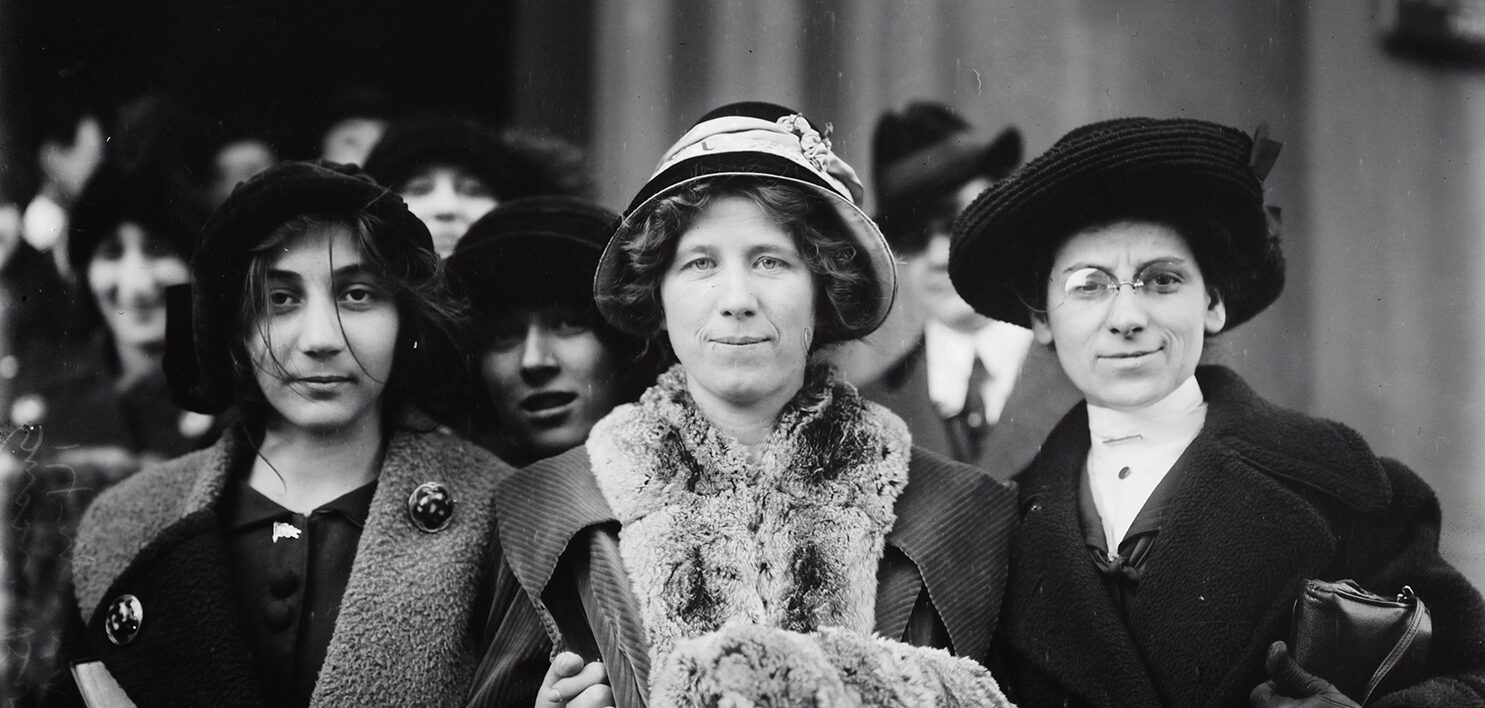 A black and white photo with women dressed up.