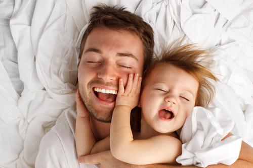 A father holding his child, laughing.