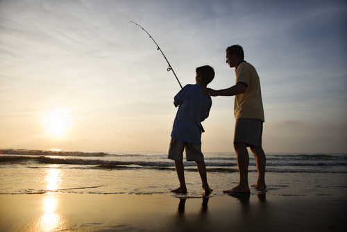 A father and son fishing by the ocean.