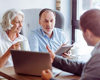 An attorney talking to a older couple about social security benefits.