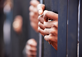 Person's hand holding prison door