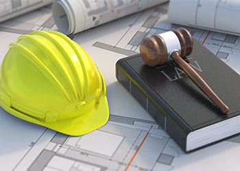 Gavel placed on book with construction safety helmet on side