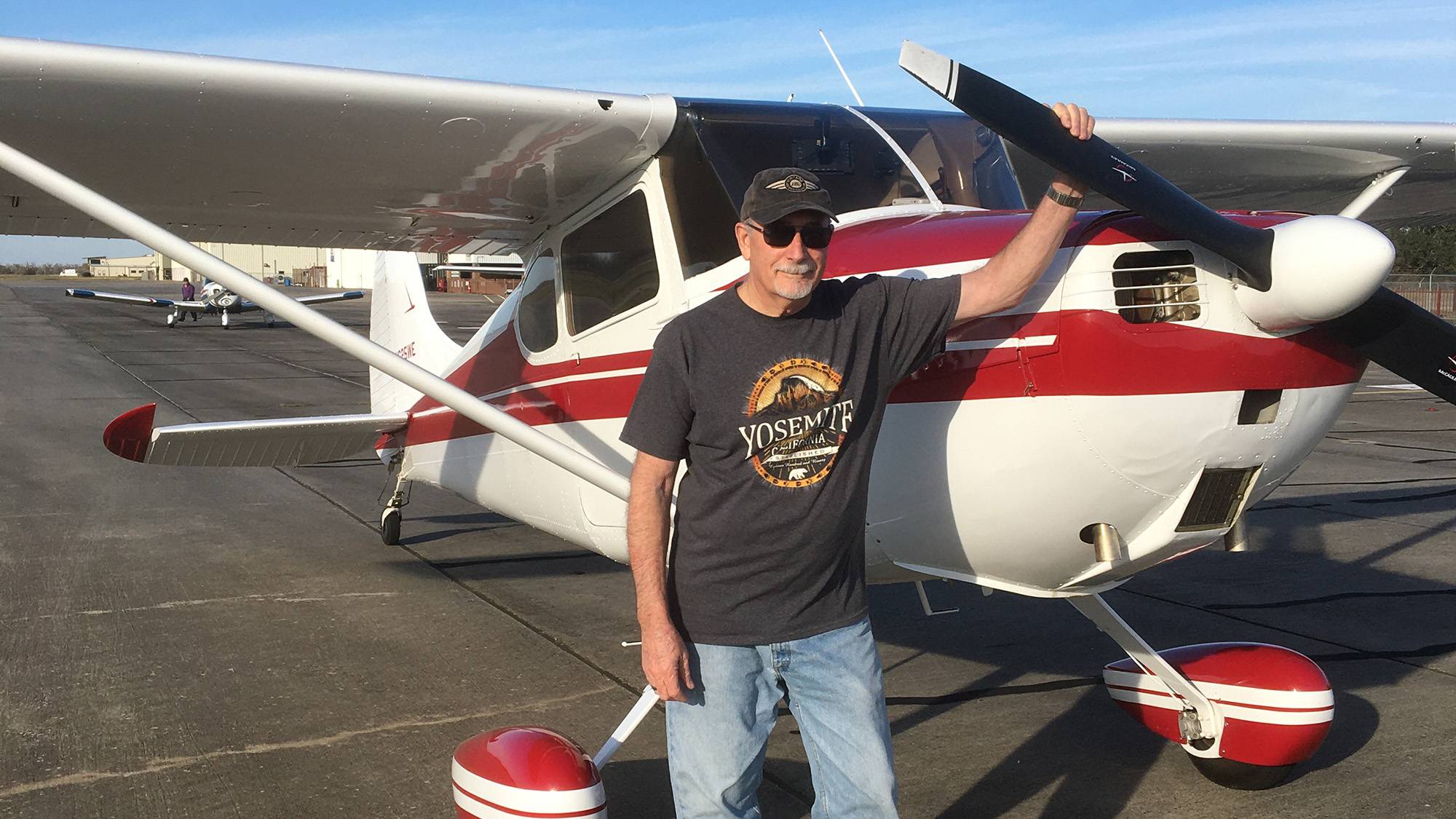 William "Bill" G. Harger standing next to a red and white plane.