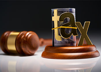 Judge's gavel with dollars in roll with single word tax